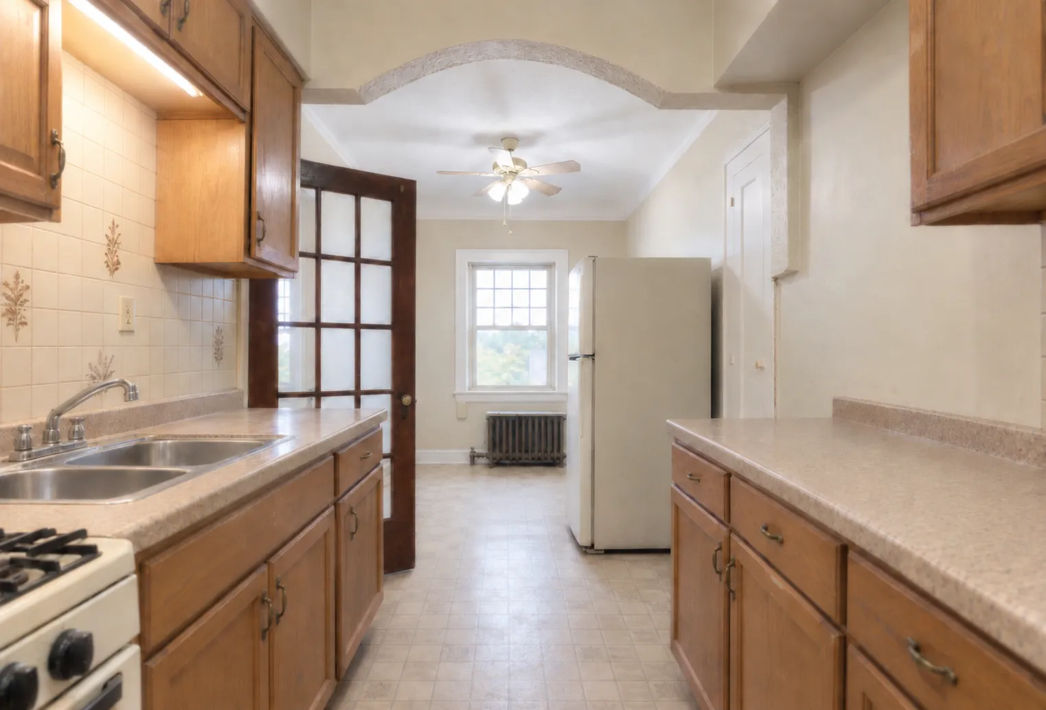The galley kitchen before work: oak cabinets, laminate counters and older white appliances