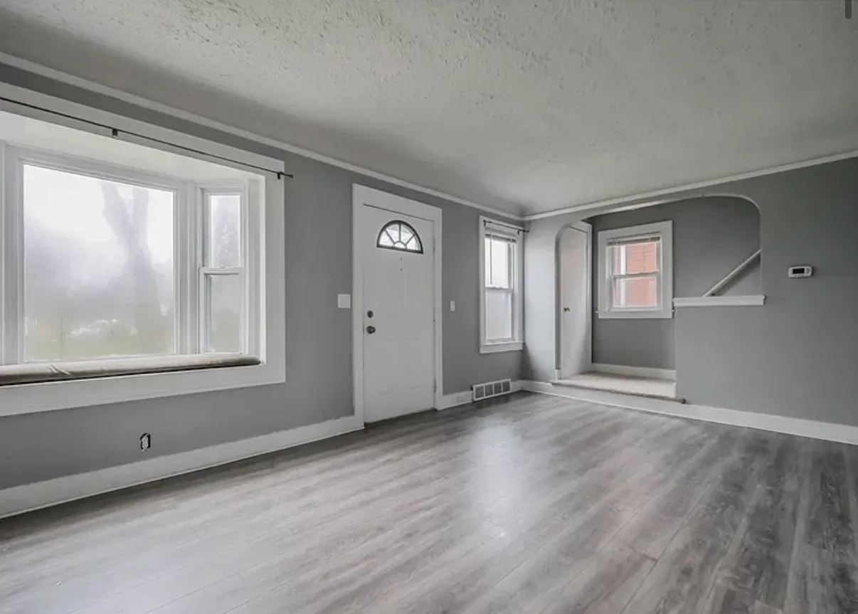 Living room with a bay window, refinished floors and an arched opening to the stair